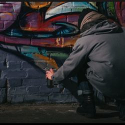 Raise the Age Law: Youth Spray Painting Graffiti on Wall